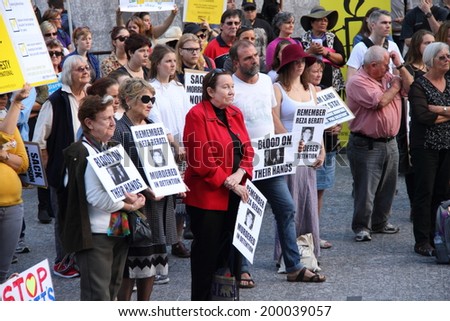 BRISBANE, AUSTRALIA - JUNE 22 : Unidentified protesters holding anti liberal government and reza berati remembrance signs  attending World Refugee Rally June 22, 2014 in Brisbane, Australia