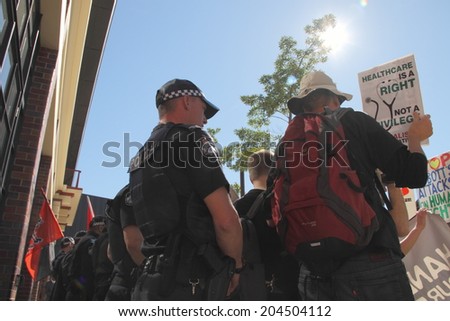 BRISBANE, AUSTRALIA - JULY 12 : Unidentified protesters in front of police cordon outside Liberal National Party national conference July 12, 2014 in Brisbane, Australia
