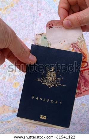australian passport and holder on top of paris map with cash exchanging hands