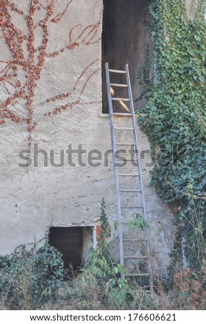 Ancient ruins of a rural house with old vintage ladder on the wall