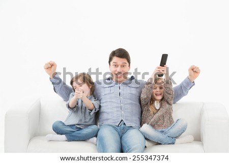 Father son and daughter watching television sitting on the couch on a white background
