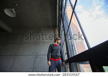 Man in sportswear looking out the window. Creative portrait