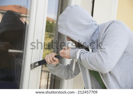 burglard breaking a window for home theft