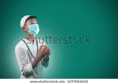 Coronavirus Covid-19 and Air pollution pm2.5 concept. Muslim young men who are praying and wearing hygiene protective mask for protect pm2.5. epidemic virus symptoms with green background Imagine de stoc © 