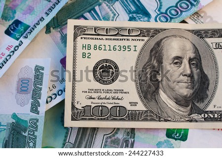 A hundred dollar bill on the background of Russian roubles