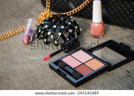 Women\'s accessories: eyeshadow, lip gloss, nail polish, clip hair, necklace, black handbag