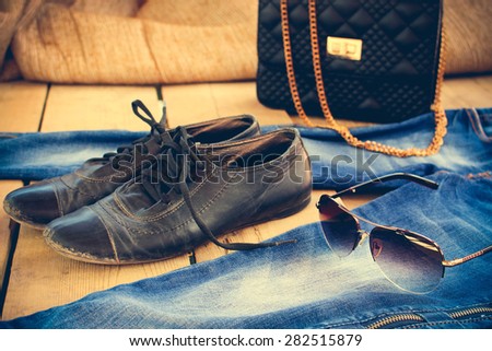 Sunglasses, jeans, handbag and old shoes. Toned image.