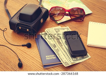 Travel set: passport, money, mobile phone, blank notebook, camera, road map, sunglasses, headphones. Summer accessories. Toned image