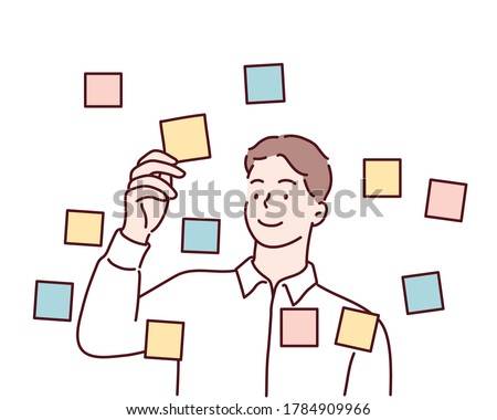 Focused young male employee writes ideas on sticky note on glass wall in office. Hand drawn style vector design illustrations.
