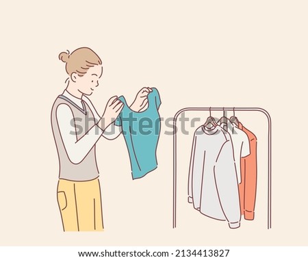 Beautiful young woman near rack with clothes making chioce. Hand drawn style vector design illustrations.