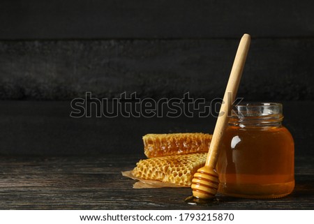 Honeycombs, jar with honey and dipper on wooden background
