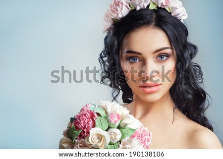 Beautiful young girl with a floral ornament in her hair on a blue background