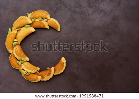 Ramadan kareem with qatayef arranged in shape of crescent moon. Traditional middle estern ramadan sweets. Iftar food concept. Top view, copy space                           