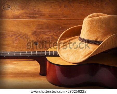 Guitar and cowboy hat on wood background for text or design