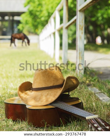 cowboy hat and guitar on American ranch landscape.Country music