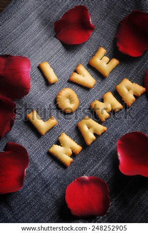 Cookies ABC in the form of word I LOVE MAMA alphabet with red rose petal on old jean background, Valentines day