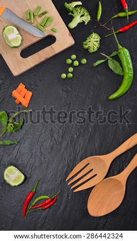 Frame of vegetables, herbs. chilli, kitchenware on black background.