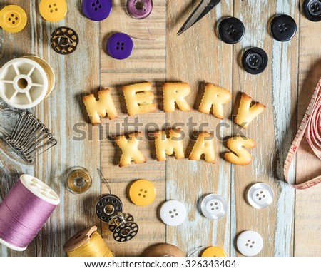 ABC Cookie in the form of word MERRY XMAS and sewing tools on vintage wooden background. Copy-Space
