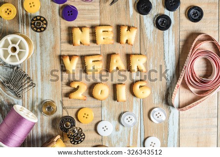 ABC Cookie in the form of word NEW YEAR 2016 and sewing tools on vintage wooden background. Copy-Space
