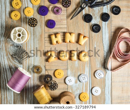 ABC Cookie in the form of word HNY 2016 and sewing tools on vintage wooden background. Copy-Space