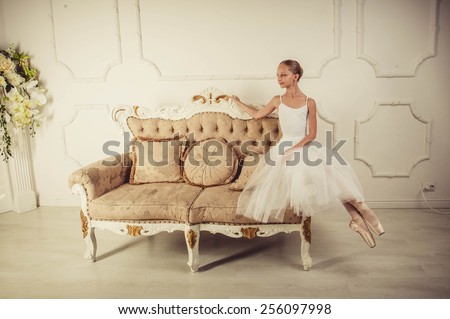 young ballerina is dancing in white hall. She in classic dress is clothed.