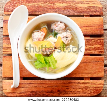clear soup with pork in white plate put on wooden background, Thai cuisine.
