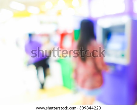 Blurred image of woman use ATM machine in bank to take money or do something about financial.