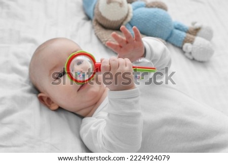 cute baby is playing with a rattle on a white bed. Attention concentration, grasping an object by infants Сток-фото © 