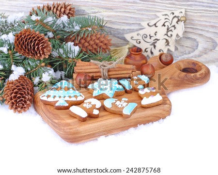 Ginger cookies on a board and fir-tree branches with cones on a white background. Christmas background.