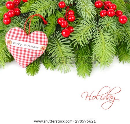 Red berries and red checkered textile heart on fluffy branches of a Christmas tree on a white background. A Christmas background with a place for the text.