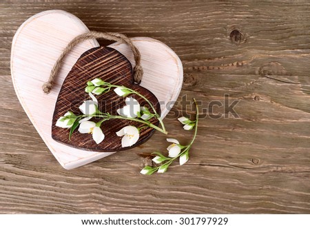 Two wooden hearts and branch of a jasmine on a wooden background. A background for St. Valentine\'s Day.