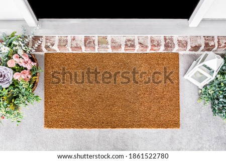 Blank natural door mat in front of entrance door with flowes, doormat mockup Foto d'archivio © 