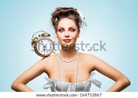 A beautiful vintage pin-up girl in a white wedding dress with a retro alarm clock on her shoulder in the morning.