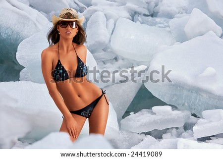 Hot\'n\'cold. A hot sexy woman in a tiny bikini surrounded by gigantic blocks of ice.