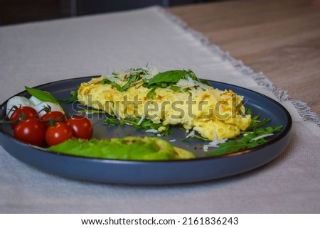 French omelette dish. Delicous homemade french omlette filled with cheese. Plating with fresh vegetables like avocado, cherry tomatoes, but also basil and mozzarella. Stock fotó © 