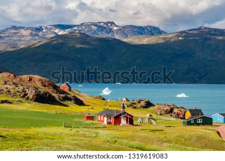 The view of Narsarsuaq in Greenland and the bay with icebergs. In the background mountains and blue sky with some clouds.
