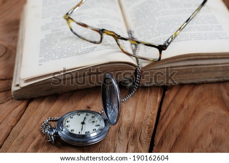 old book vintage watches glasses on wooden board