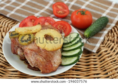 roasted turkey meat with pineapple and kiwi on a plate with tomato and cucumber