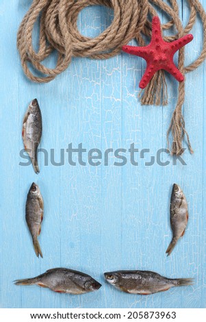 frame of dried fish, starfish and twisted rope on the background of painted wooden tablets
