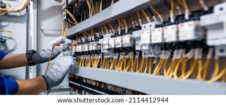 Electricity and electrical maintenance service, Engineer using measuring equipment tool checking electric current voltage at circuit breaker terminal and cable wiring main power distribution board. Photo stock © 