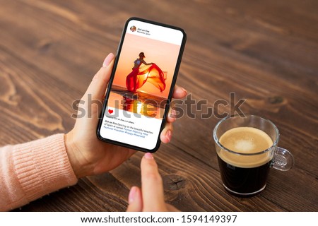 Woman sitting in cafe and viewing someone's photo on mobile phone.