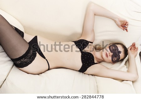 Woman lying on the sofa while wearing lingerie and mask