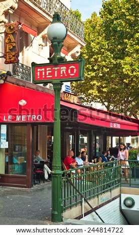 PARIS, FRANCE - 07 SEPTEMBER, 2014: Metro sign with a bar in the background on 7 September, 2014 in Paris, France. Paris is one of the most populated city in Europe full of bars and cafes.