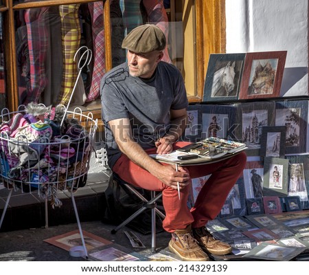 Edinburgh, Scotland, UK - September 2012; A painter street artist, sits in front of a shop to paint his works and then sell them to tourists in the city of Edinburgh, the capital of Scotland.