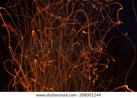 The dancing sparks from a fire on a black background.