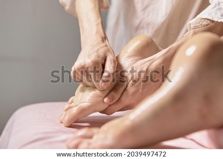 Close up reflexology foot massage. Professional therapist giving leg and foot massage to a woman in spa. Female massage therapist massaging clients legs. Body relaxation and skin care