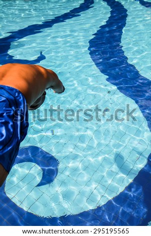 Young man jumping into pool with water splashing all around him
