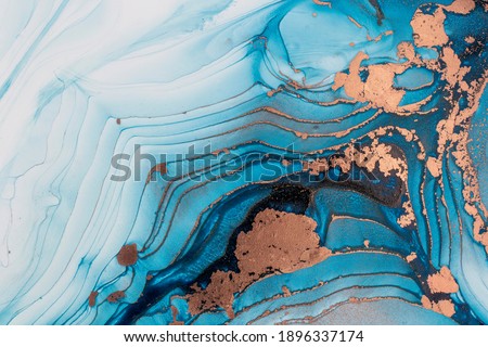 Luxury abstract fluid art painting in alcohol ink technique, mixture of blue and gold paints. Imitation of marble stone cut, glowing golden veins. Tender and dreamy design.