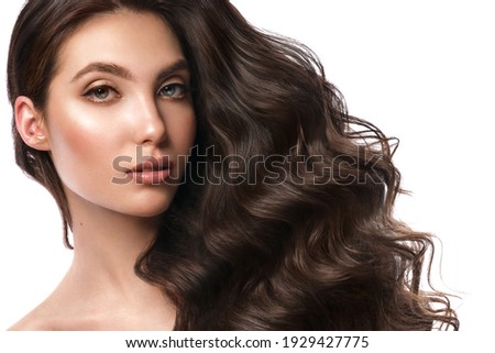 Beautiful brown-haired girl with a perfectly curls hair, and classic make-up. Beauty face and hair. Picture taken in the studio.