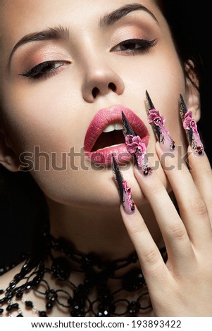 Beautiful girl with long nails and sensual lips. Portrait shot in the studio on a black background.